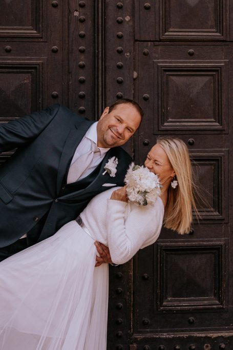 Ein Brautpaar posiert vor einer historischen, rustikalen Tür.